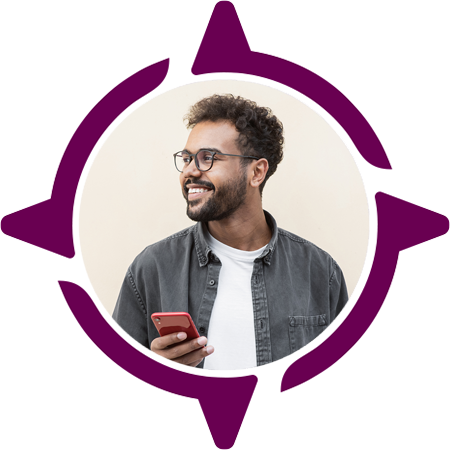 Young adult man looking to his right, holding a cell phone, and smiling